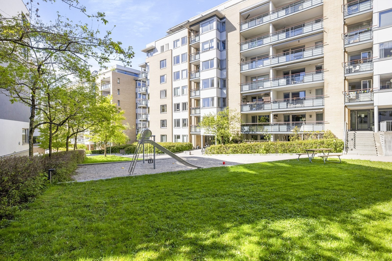 Sameiene på Elvebredden har hyggelige grønne fellesområder med sitteplasser og lekeområder foran boligene. Galleribilde