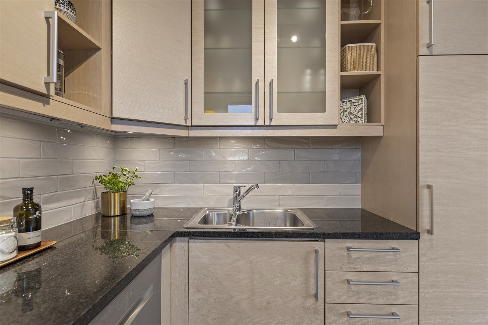 Kjøkkeninnredning med glatte finerte fronter. Eksklusiv granitt benkeplate med skyllekum og ettgreps blandebatteri. Fliser over kjøkkenbenken. Belysning under overskap. Galleribilde