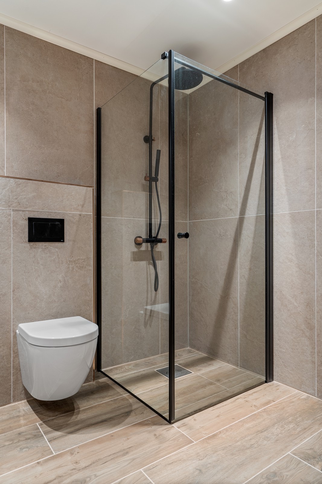 Delikat, med store fliser, vegghengt toalett, og eksklusiv dusjsoneløsning med sorte detaljer. Varmekabler i gulv. Galleribilde