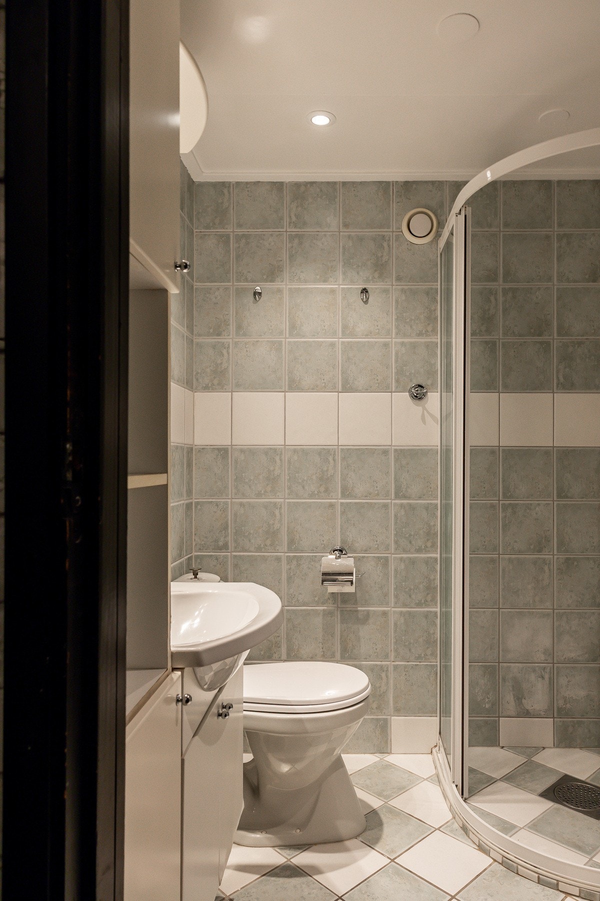 Badet er flislagt og har dusjnisje med innfellbare dusjdører, servant med ettgreps blandebatteri og gulvstående toalett. Galleribilde