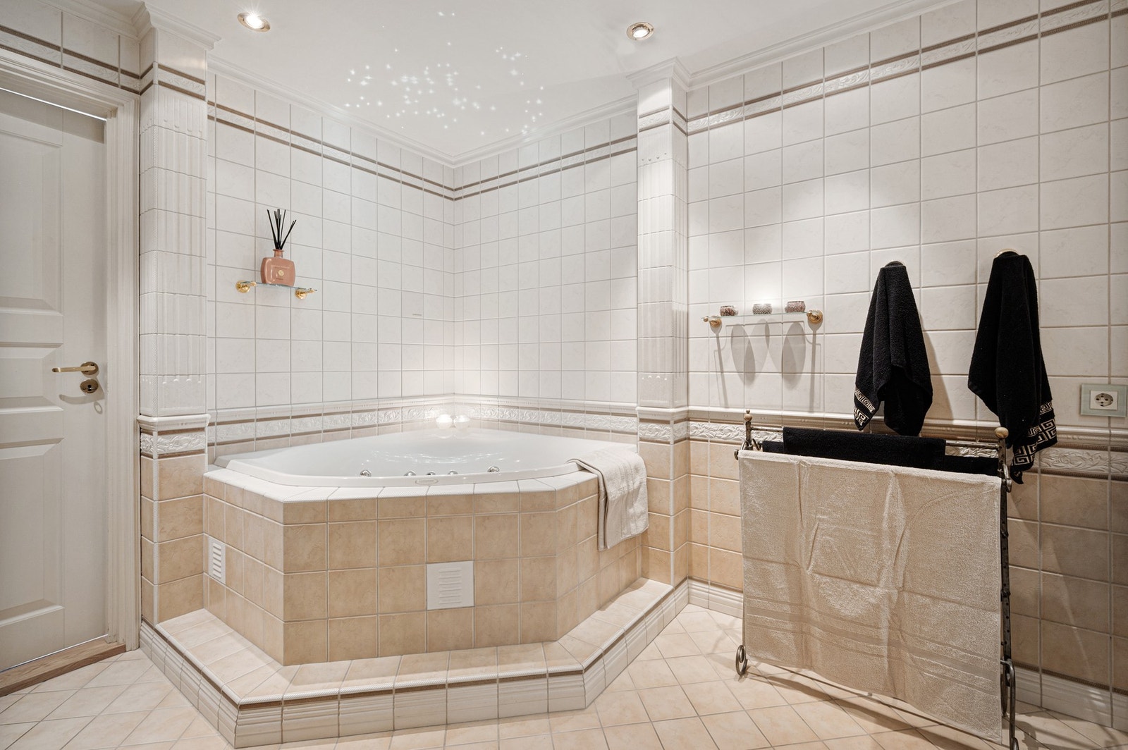 Stilrent baderom som består av dusjhjørne, boblebadekar, kran og avløp for vaskemaskin, plassbygd baderomsinnredning med dobbel servant og speil. Galleribilde