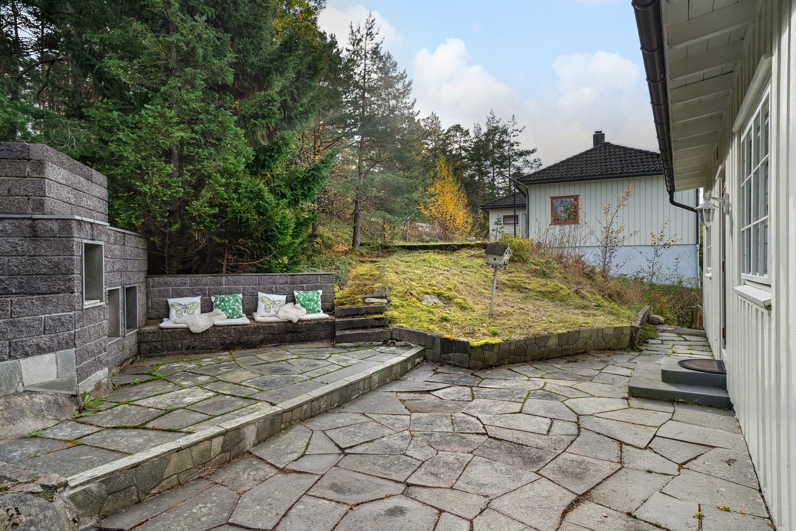 Pent uteområde med steinbelagt terrasse, sofagruppe og peis - perfekt for hyggelige kvelder utendørs. Galleribilde