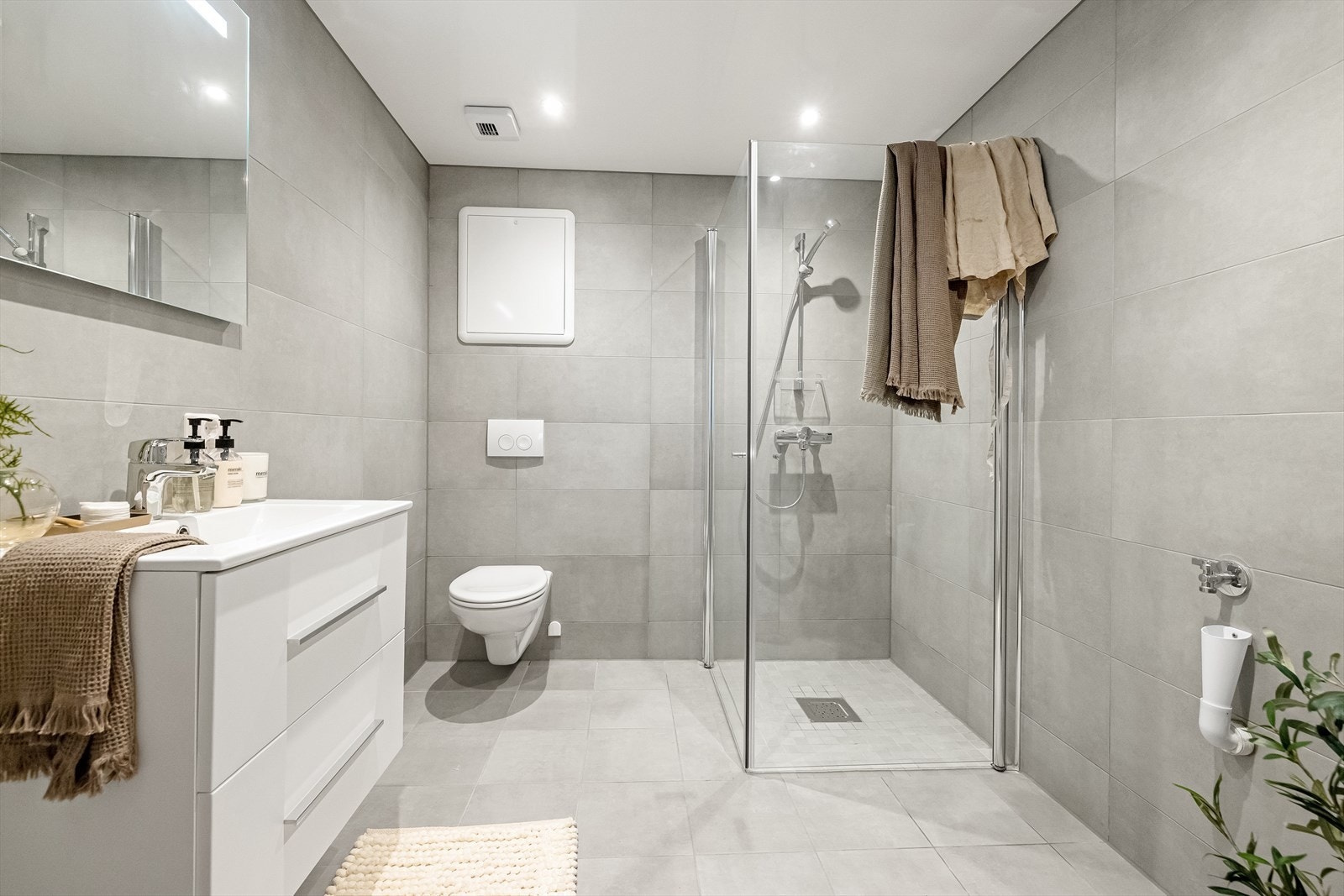 Pent og moderne baderom med dusjhjørne og opplegg for vaskemaskin. Galleribilde