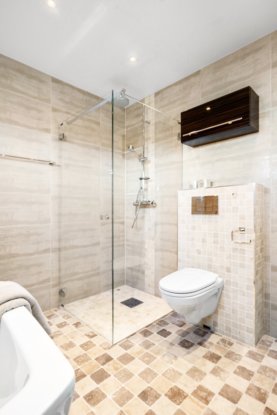 Videre har badet et romslig dushjørne med glassdører og vegghengt toalett. Galleribilde