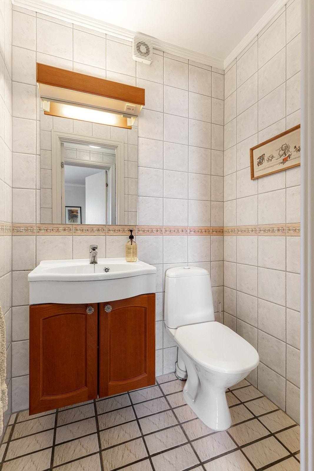 Toalettrom med gulvflate belagt med fliser og gulvvarme. Flislagte vegger. Malte flater i himling. Vegghengt servantinnredning. Ovenpåliggende servant med armatur. Gulvstående toalett. Galleribilde