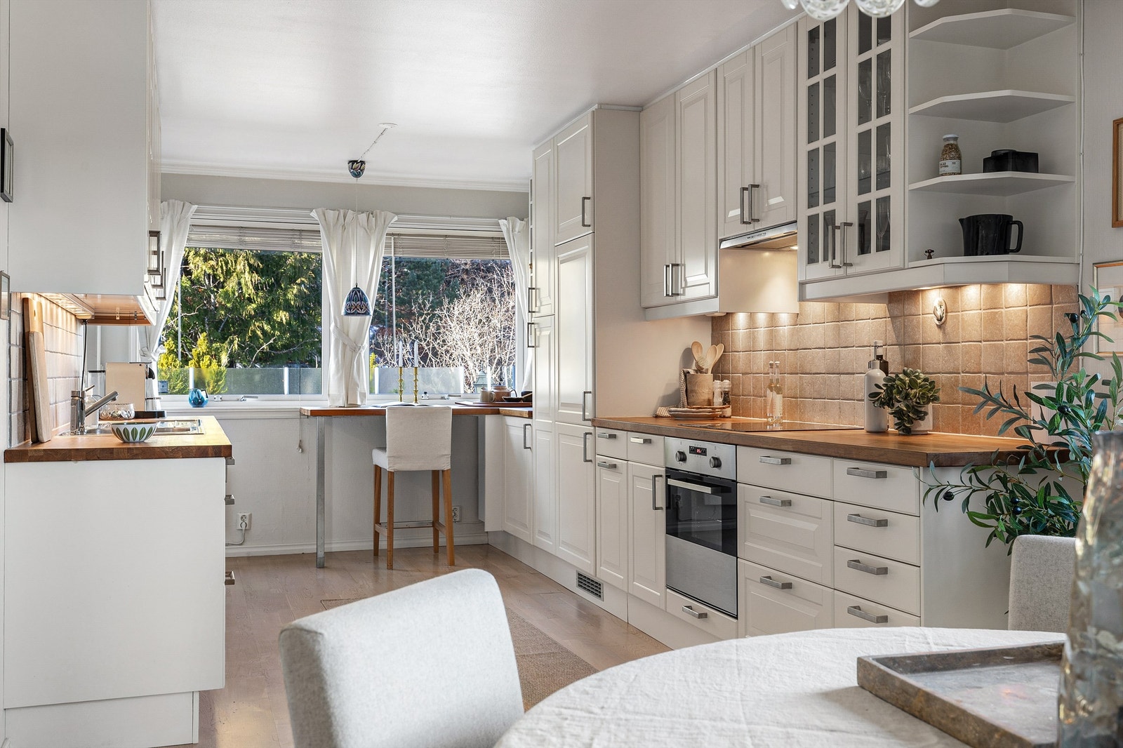 Kjøkken med innredning fra rundt 2010. Profilerte fronter. Benkeplate av tre. Nedfelt kjøkkenvask med armatur. Benkeskapsbelysning og stikkontakter over kjøkkenbenk. Galleribilde