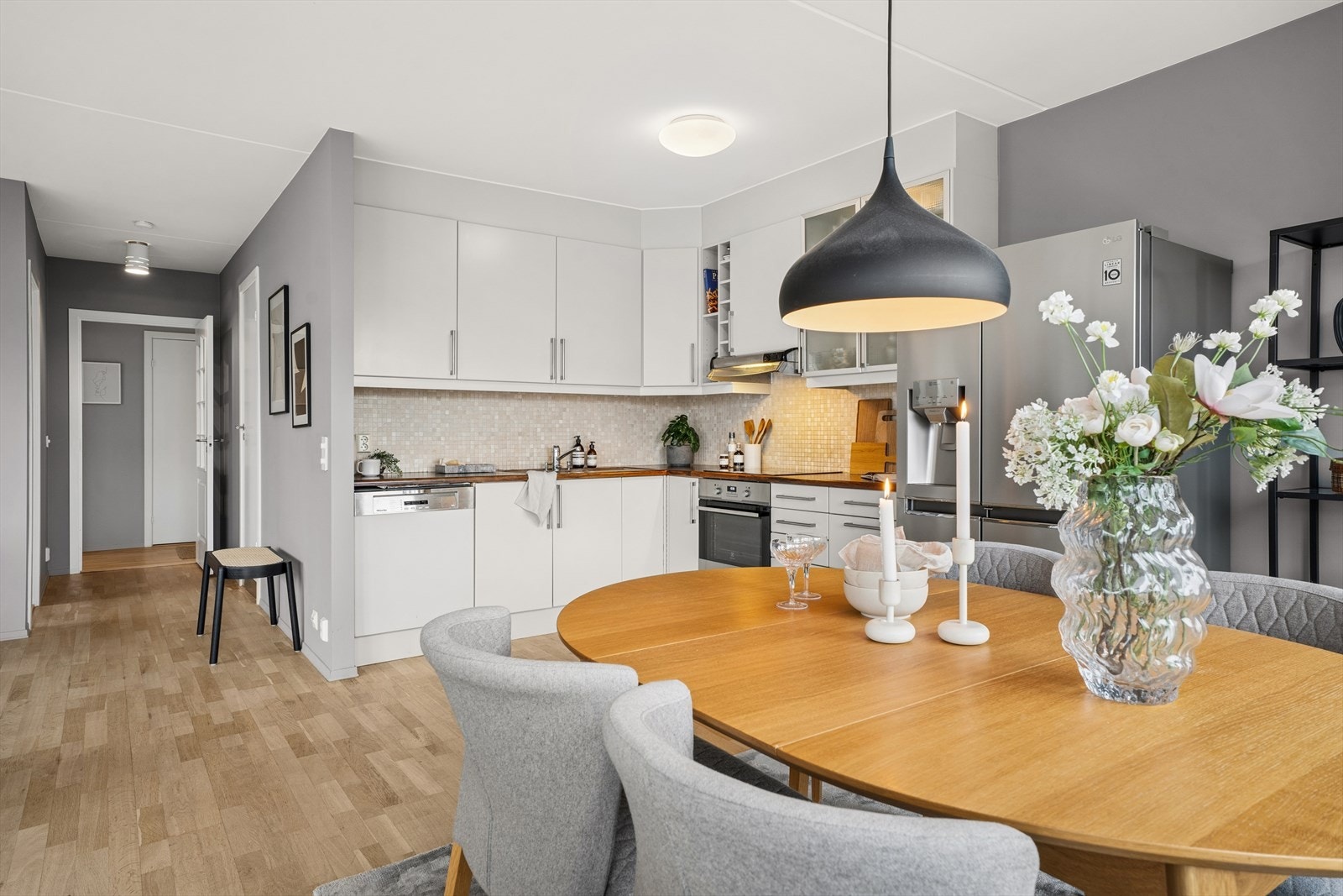 Stuen har åpen kjøkkenløsning med hvitevarer og en hyggelig spisestue foran store vinduer som slipper inn mye sollys. Galleribilde