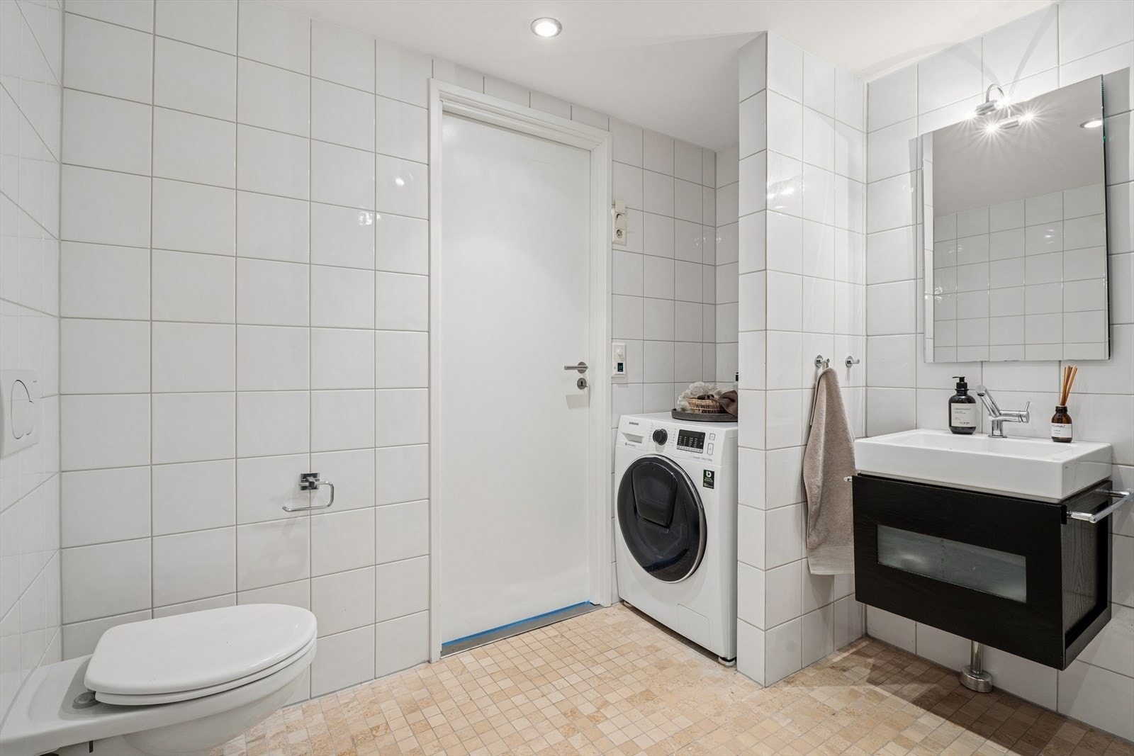 Baderommet er innredet med veggmontert WC, dusj m/dusjvegger og baderomsmøbel med vask, skuffer og skap. Her er det også opplegg for vaskemaskin som følger med handelen. Galleribilde