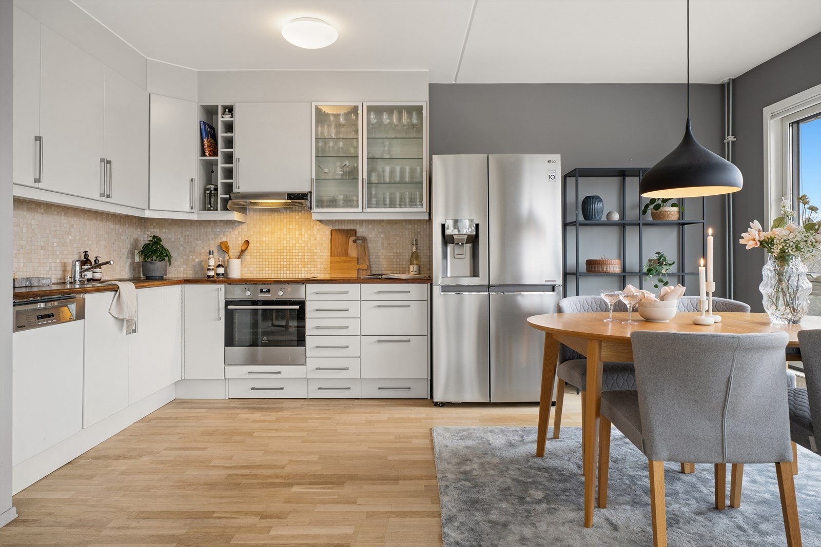 Tidløs kjøkkeninnredning bestående av hvite glatte fronter, mekanisk vifte, integrert koketopp/ovn og oppvaskmaskin. Galleribilde