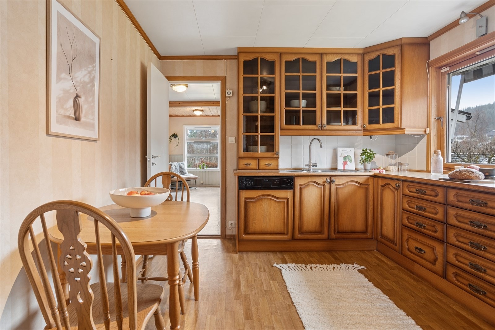 Innredningen har takhøye overskap, dels med glassfelt, og en praktisk spiseplass. Galleribilde