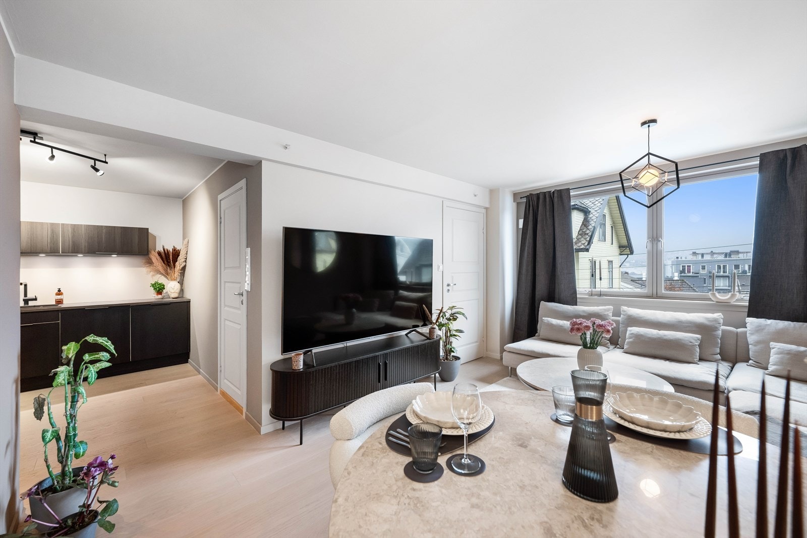 Lys og romslig stue med åpen løsning mot kjøkkenet og naturlige soner for både sofagruppe og spiseplass. Galleribilde