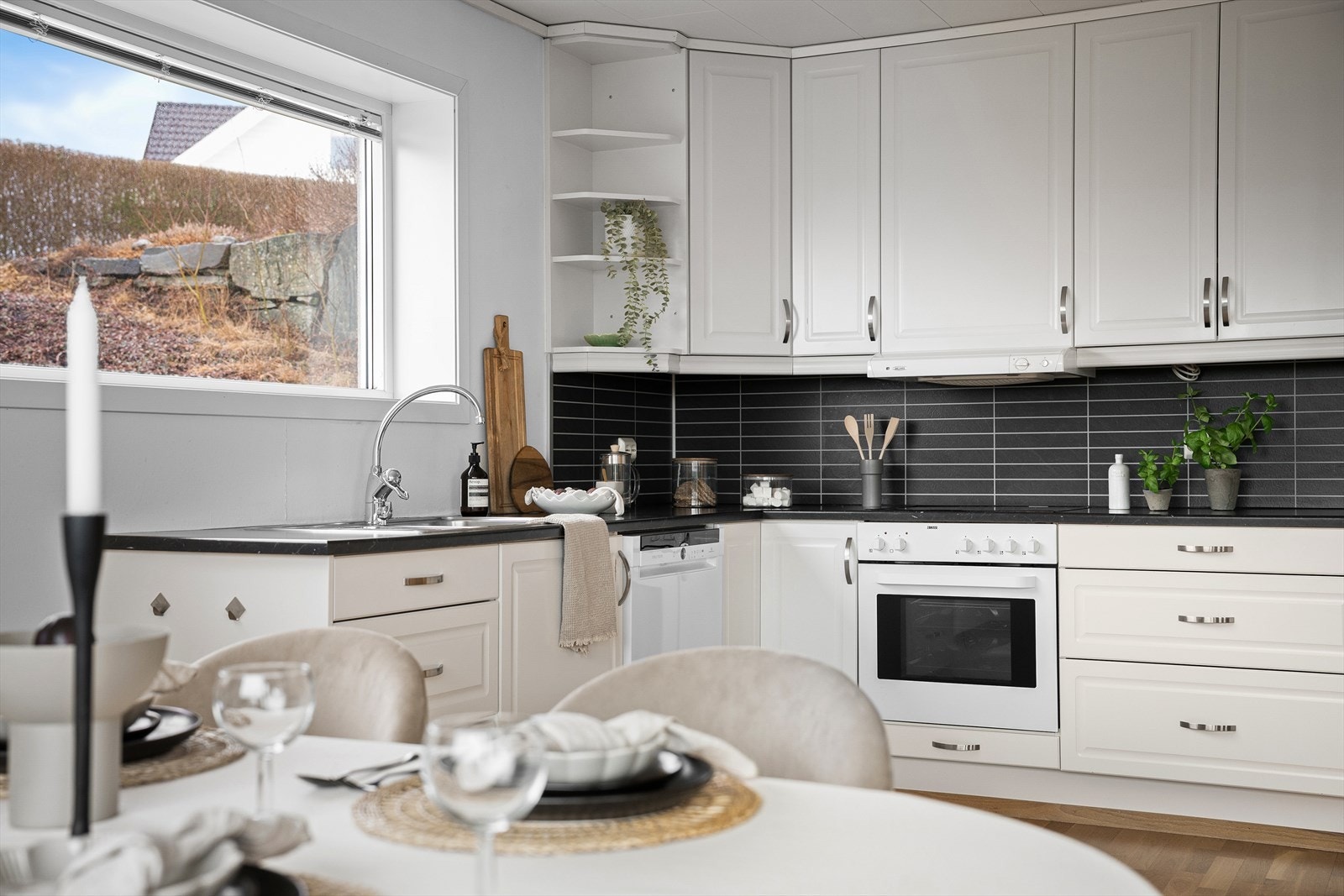 Kjøkkenet har en hvit innredning med sort laminert benkeplate og integrert stekeovn. Galleribilde