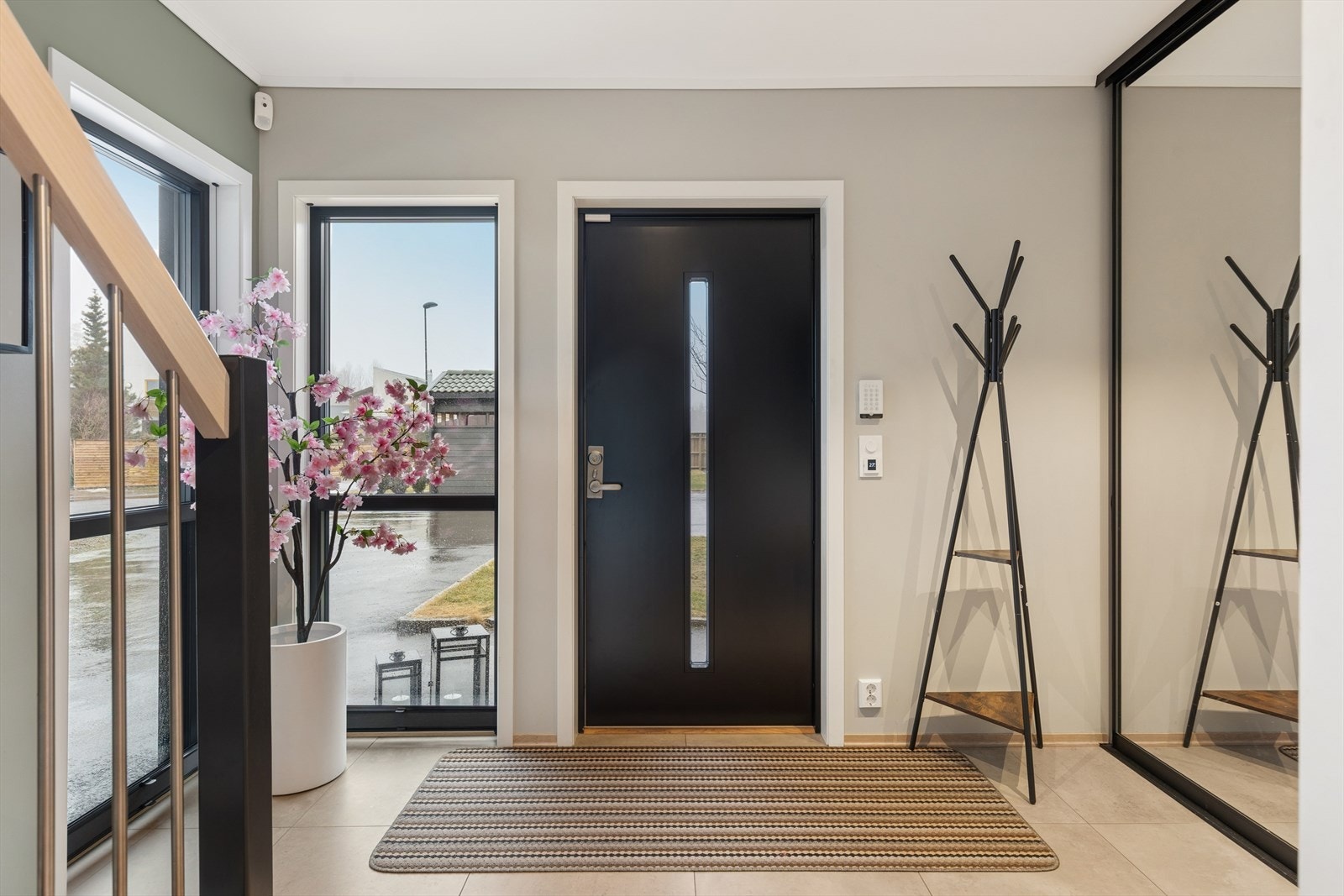 Trappen i tre med stålrekkverk leder opp til andre etasje, og den malte ytterdøren har et stilrent glassfelt. Galleribilde