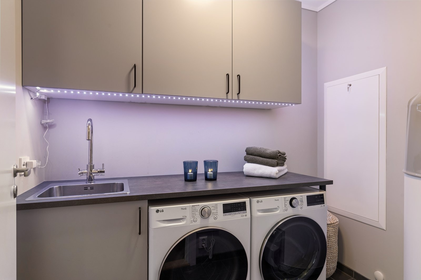 Separat vaskerom med flislagt gulv, arbeidsbenk med skyllekum og opplegg for vaskemaskin og tørketrommel. Galleribilde