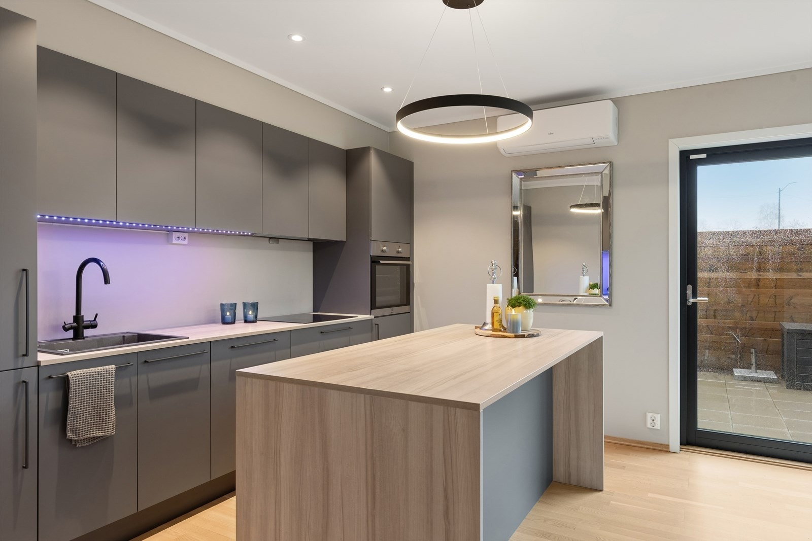 Kjøkkenet i 1. etasje har moderne innredning med slette fronter, integrerte hvitevarer og en praktisk kjøkkenøy. Galleribilde