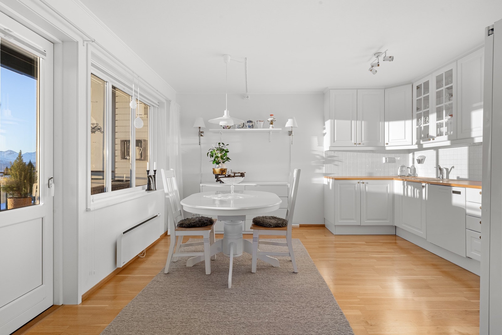 Hvit kjøkkeninnredning med underskap og takhøye overskap Galleribilde