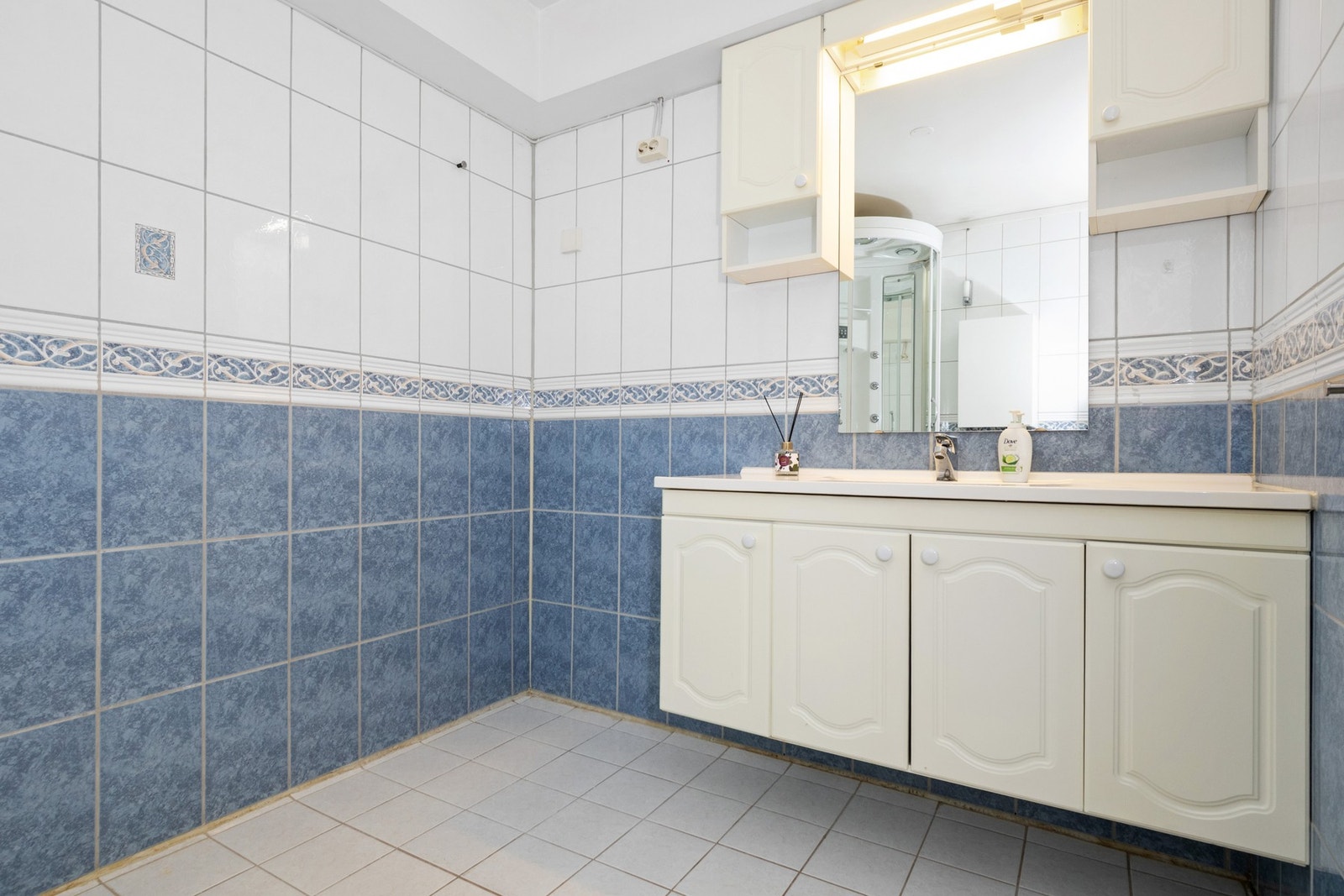 Badet er innredet med blå og hvite fliser på gulvet og store deler av veggene Galleribilde