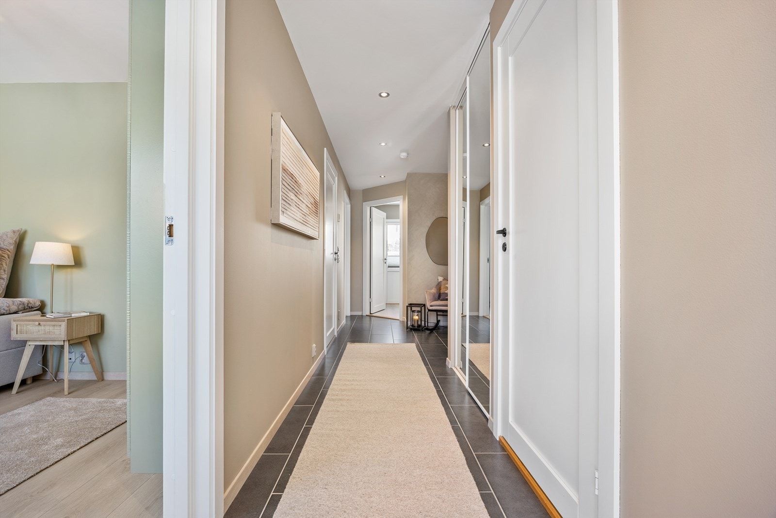 Innbydende gang i flislagt utførelse med komfort gulvvarme. Det godt med plass til å henge fra seg yttertøyet i skyvedørsgarderoben. Galleribilde