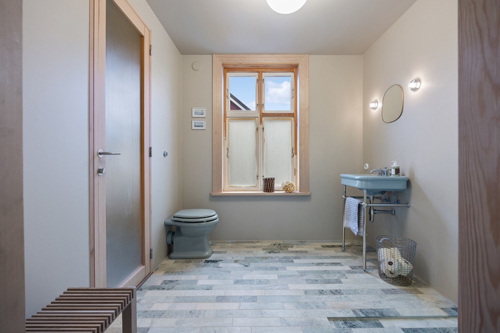 Ett elegante bad (2024) av Murmester Myhre AS, har flislagte gulv med elektriske varmekabler, fliser og malte plater på vegger, og malt himling. Adkomst fra kjøkken og trapp til kjeller samt utgang. Galleribilde