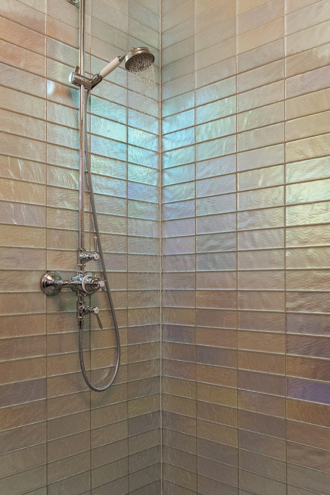 Flisene har en iriserende, perlemorsaktig overflate som gir et spill av farger når lyset treffer - fra varme beige- og sandtoner til kjølige nyanser av sølv, grønt og blått. Galleribilde