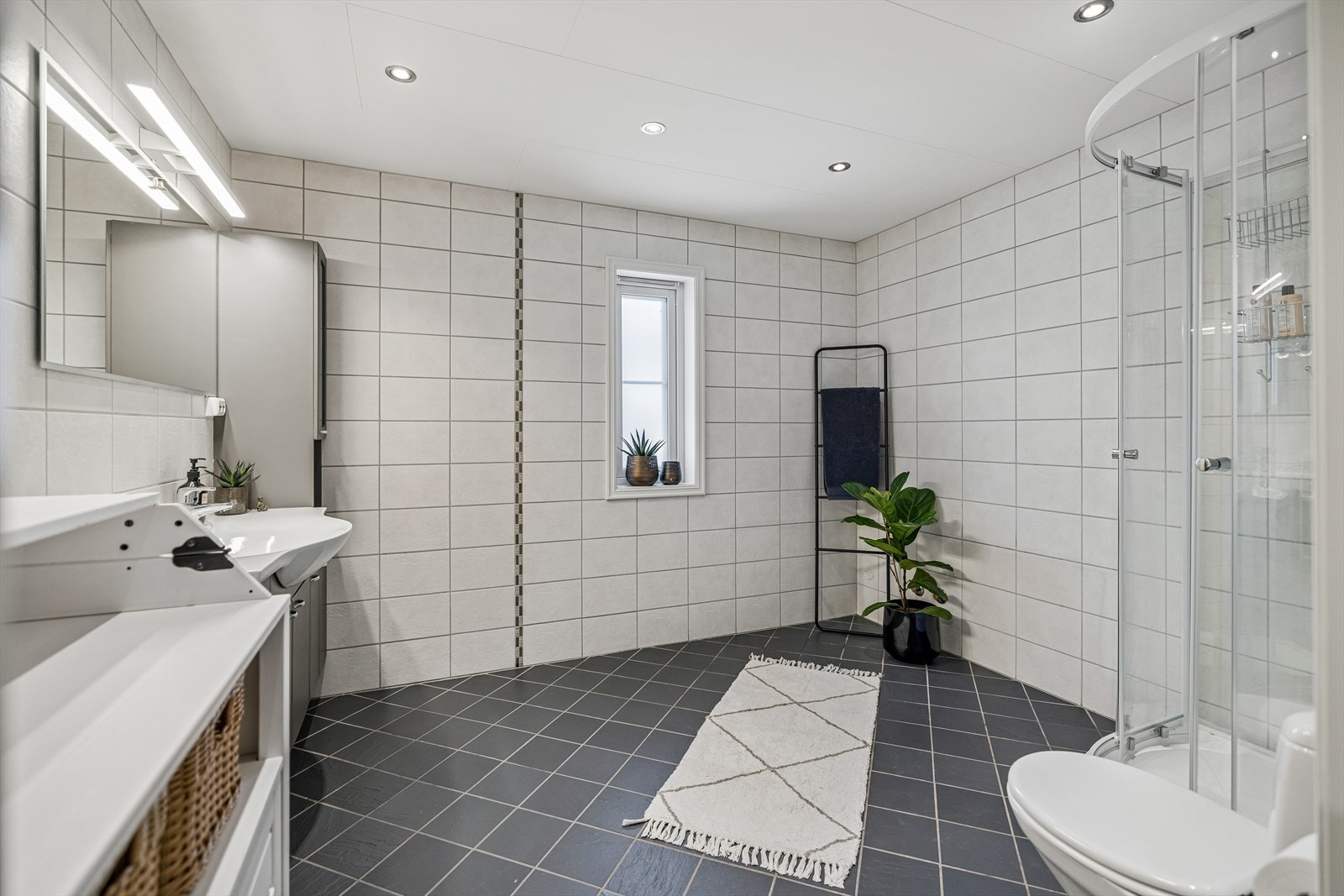 Badet er innredet med heldekkende servant, speil med lys og et praktisk dusjkabinett. Mulighet for badekar. Galleribilde