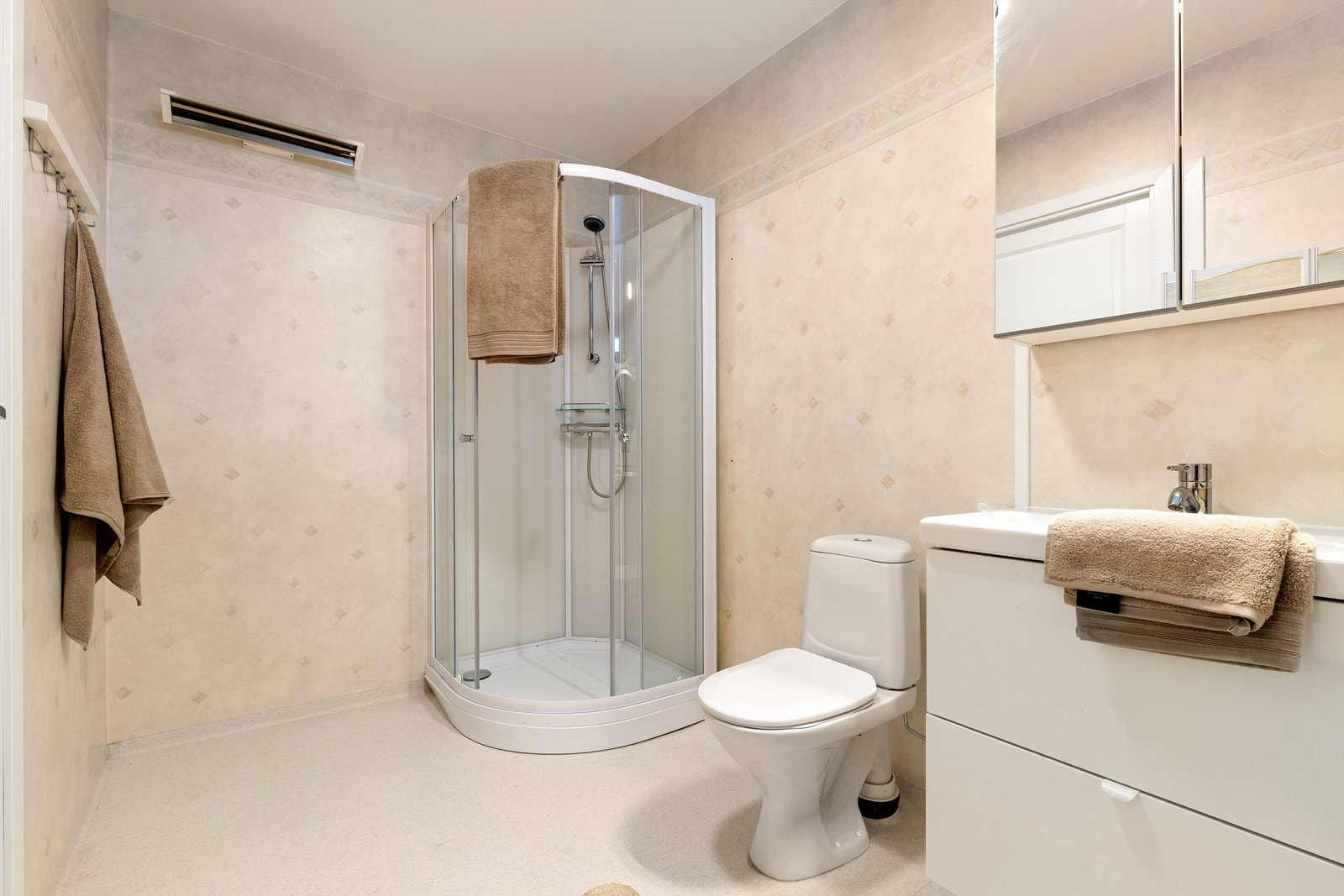 Badet i leiligheten har nytt dusjkabinett og baderomsmøbel fra 2025 men er ellers av eldre dato. Galleribilde