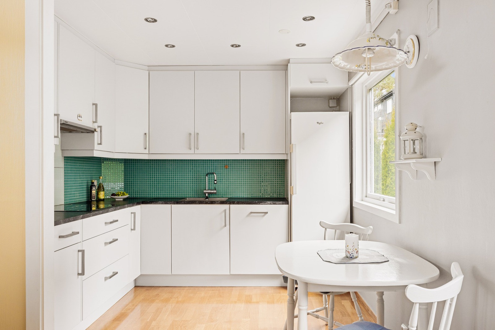 Fint kjøkken med hvitmalte glatte fronter og laminat benkeplate. Galleribilde