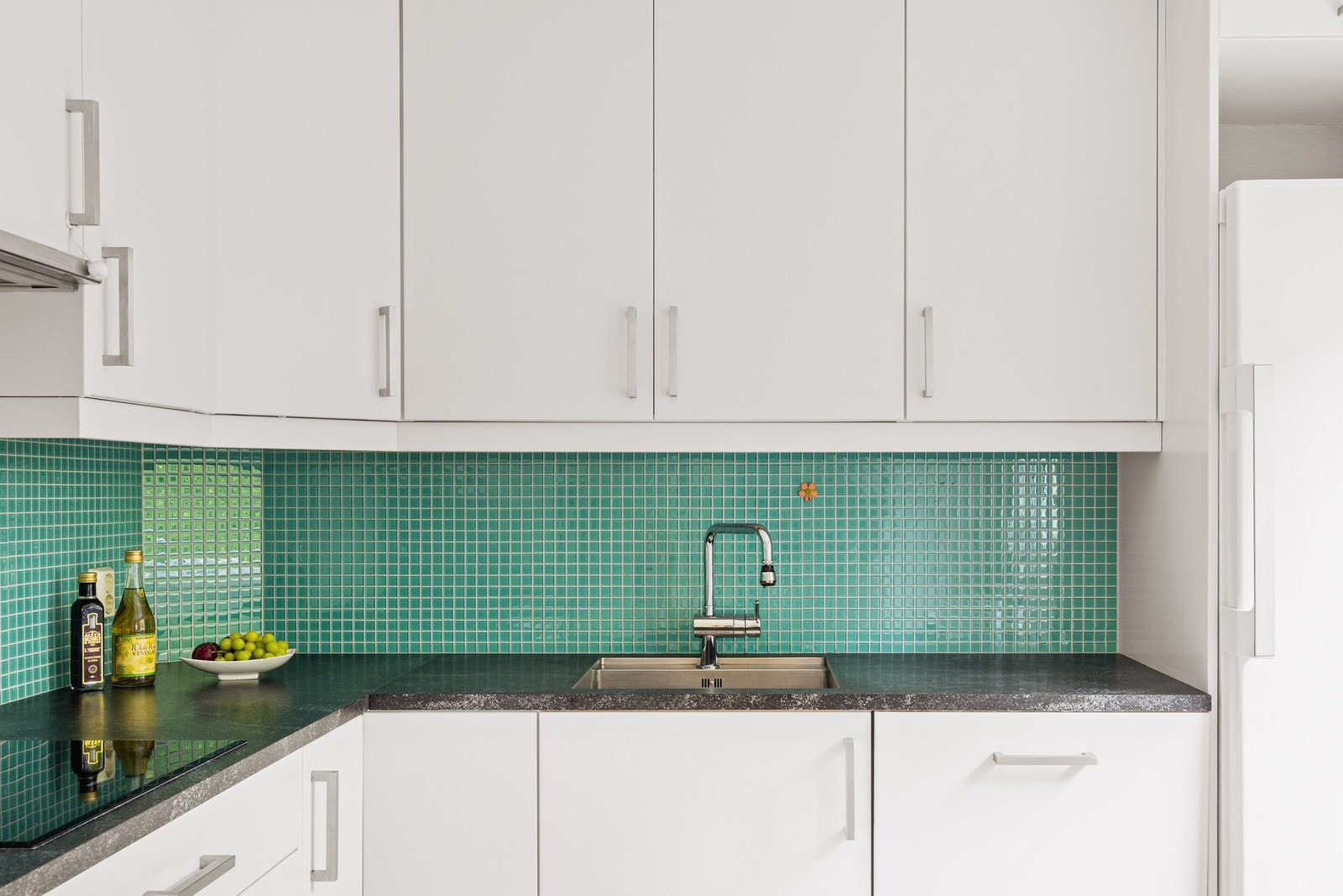 Spreke fliser over kjøkkenbenk som gjør det enklere å holde rent og skåner veggen mot fukt og søl fra matlaging. Galleribilde