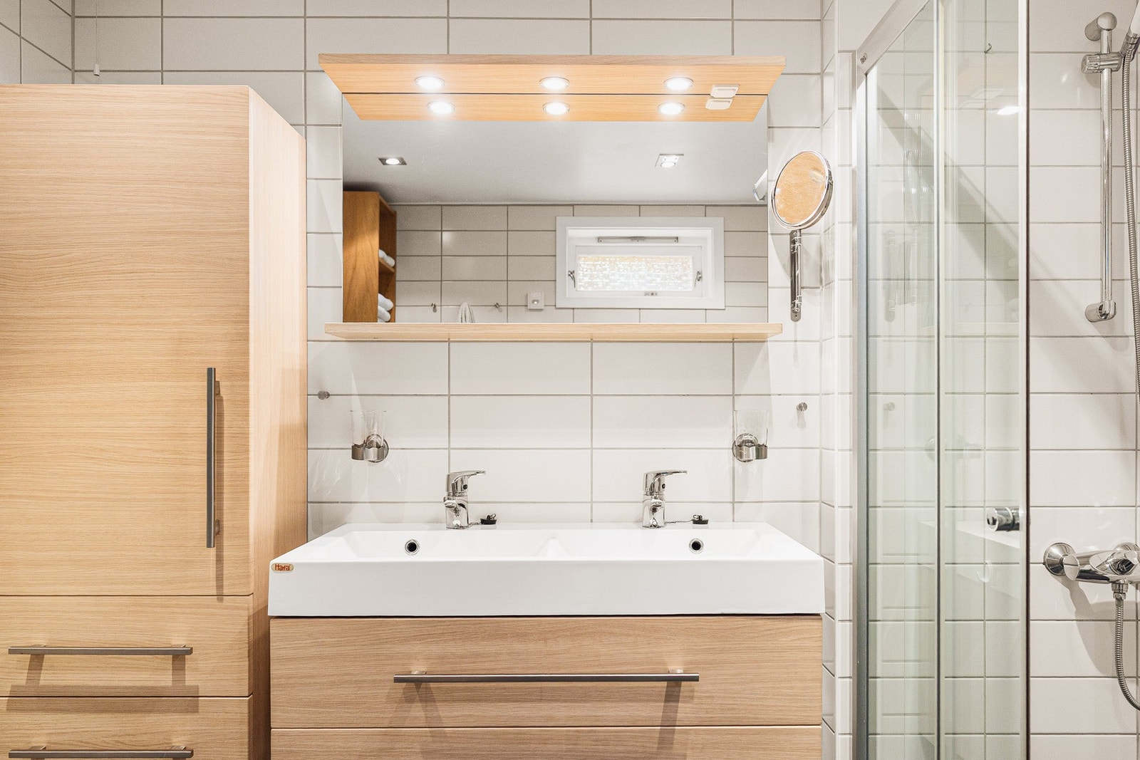 Badet er innredet med dobbelservant, toalett og dusjhjørne. Galleribilde