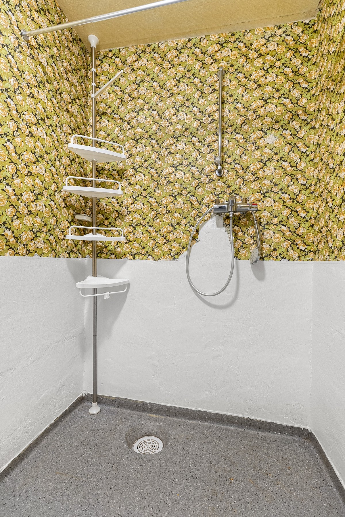 Dusjrommet har malte/tapetserte murvegger og belegg på gulvet, innredet med dusjbatteri og stand for forheng. Galleribilde