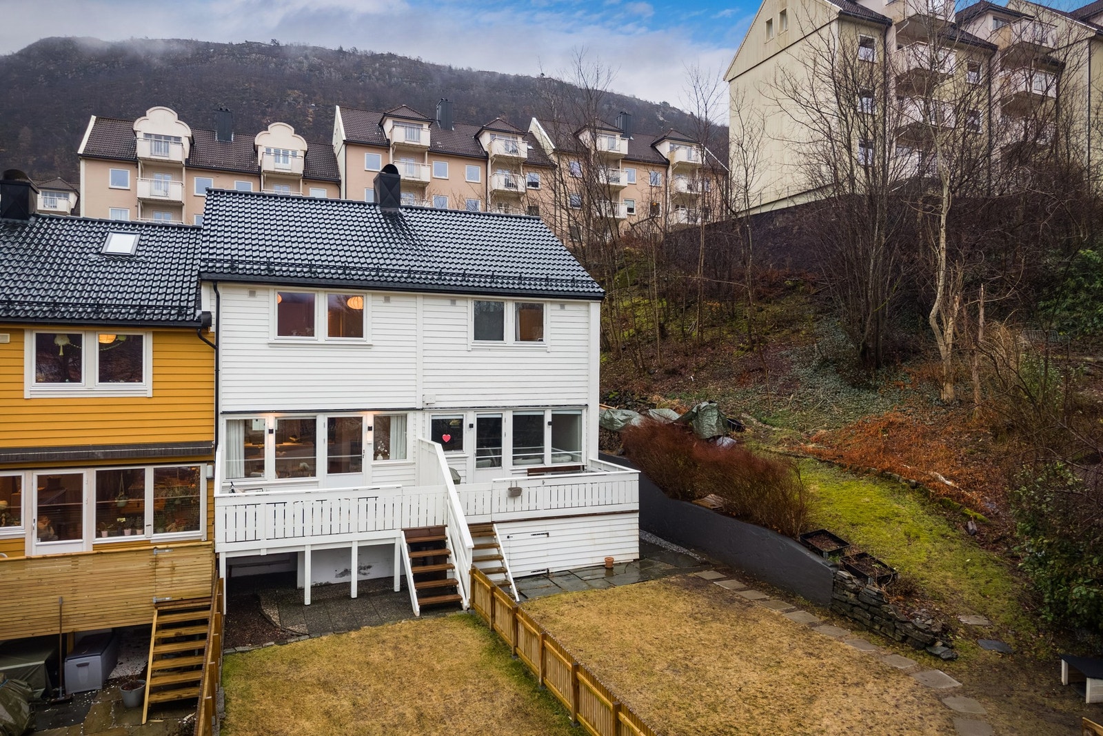 - Uteområdet er opparbeidet med plen, bed og skiferheller, og fra altanen er det trapp ned til hagen - Galleribilde