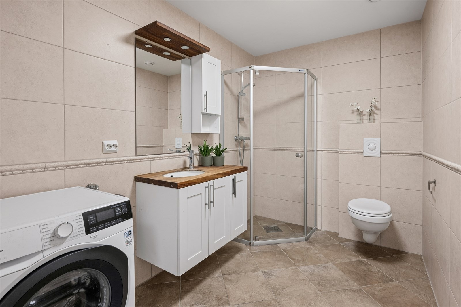 Badet er tidløst innredet med beige fliser på gulv og vegger. I gulvet har man også varmekabler for ekstra komfort. Galleribilde