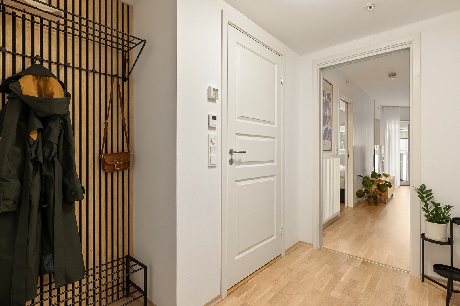 Vi starter i den romslige entréen på 4,7 kvm med hvitpigmentert eikeparkett på gulv og spilevegg montert i 2024. Galleribilde