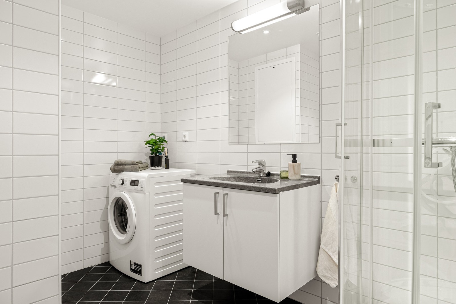 På venstre side av entréen ligger badet, som er romslig og helfliset på 5,2 kvm med gulvvarme og innfelte downlights i tak. Galleribilde