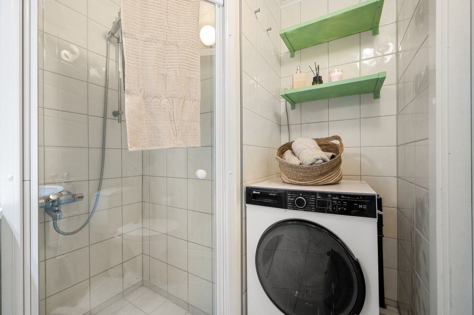 Badet har praktisk opplegg for vaskemaskin samt hyller for oppbevaring av håndklær og toalettsaker. Galleribilde