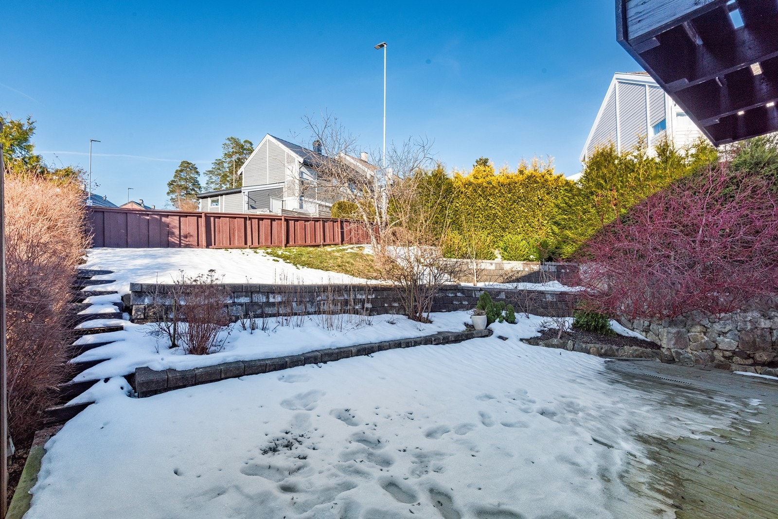 En trapp fører opp til hageflekk i terrenget - alt pent rammet inn av bed, hekk og småtrær. Galleribilde