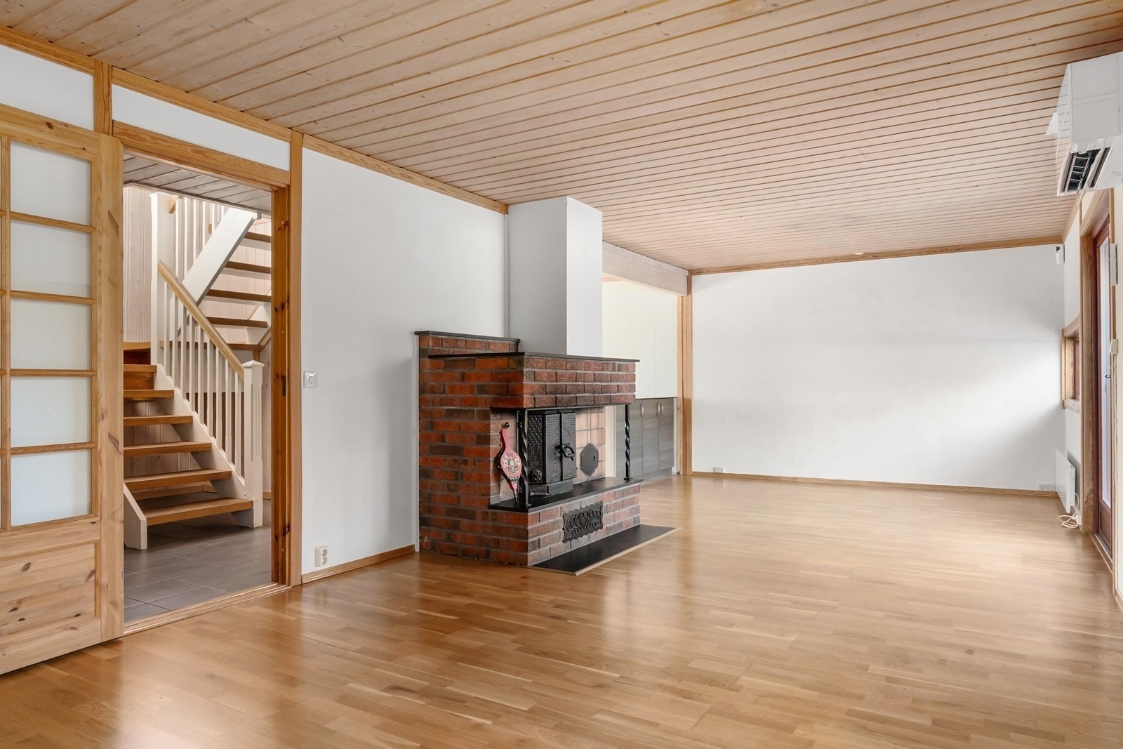 Midt i rommet er en murt peis med teglstein, i tillegg til varmepumpe for jevn oppvarming hele året. Galleribilde