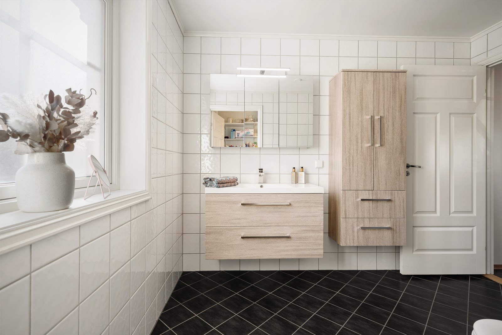 Pent flislagt bad i 1. etasje som inneholder baderomsinnredning med oppbevaring i skuffeseksjon og høyskap med skuffer. Galleribilde