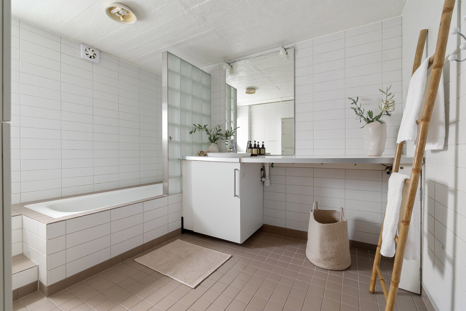 Bad/vaskerommet er innredet med innfliset badekar, møbel med nedsenket servant og speil, samt opplegg for vaskemaskin og tørketrommel integrert i innredningen. Galleribilde