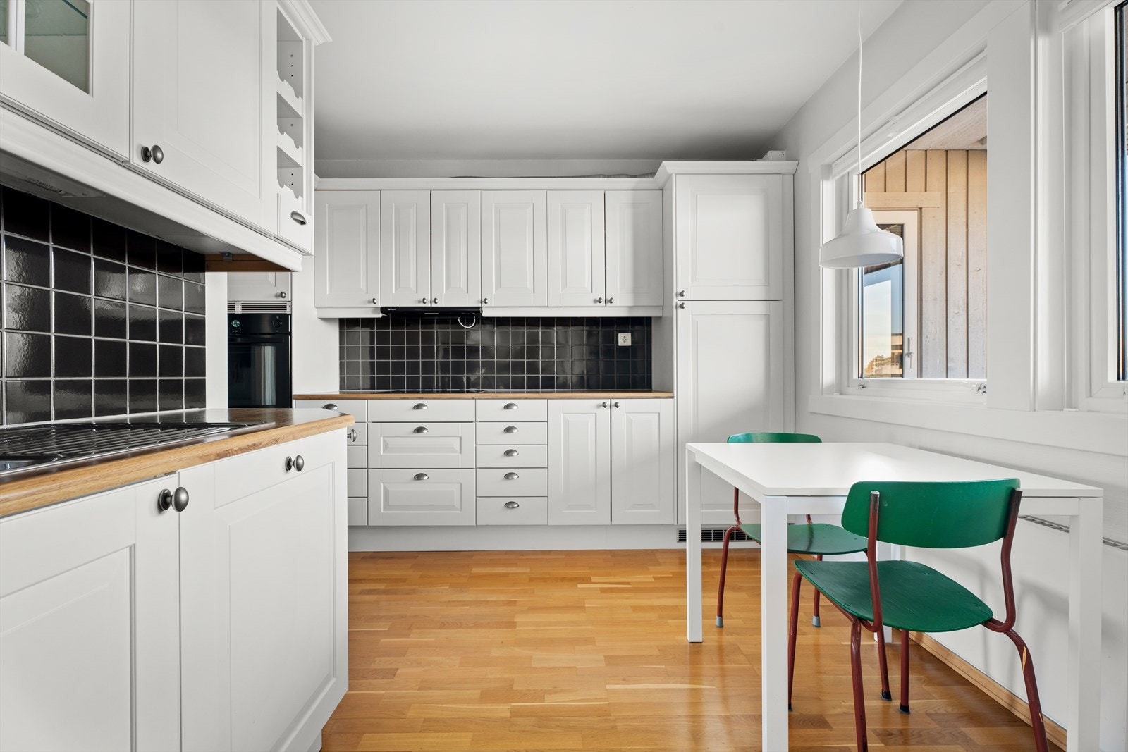 Fliser mellom benk og overskap gir en praktisk og lettstelt kjøkkensone. Galleribilde