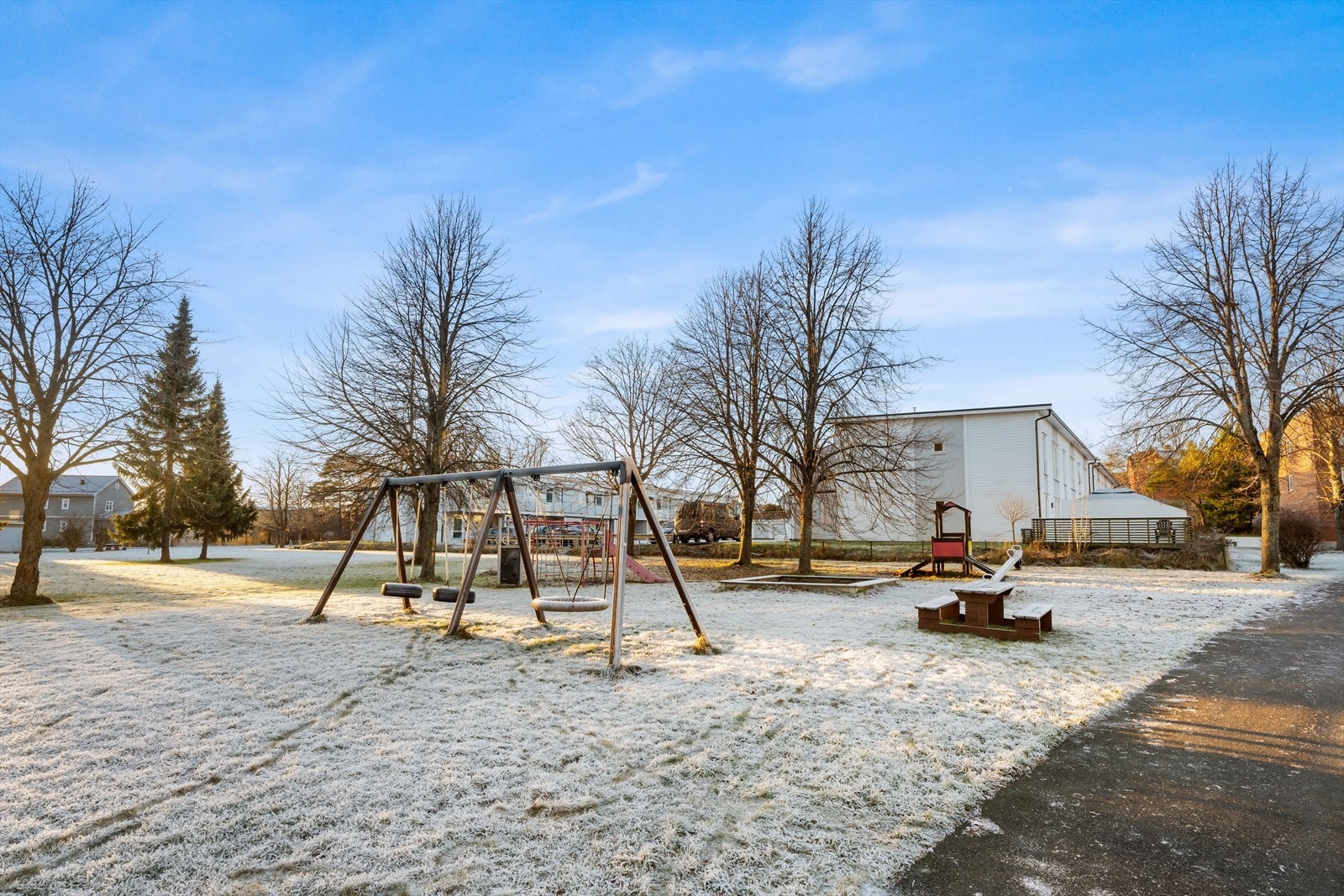 Lekeplass med husker og sandkasse gir et trygt område for barn å leke. Galleribilde