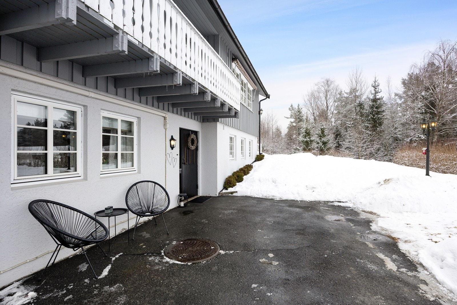 Eneboligen har et pent, overbygd inngangsparti med asfaltert adkomst og klassisk, veggmontert utebelysning. Galleribilde