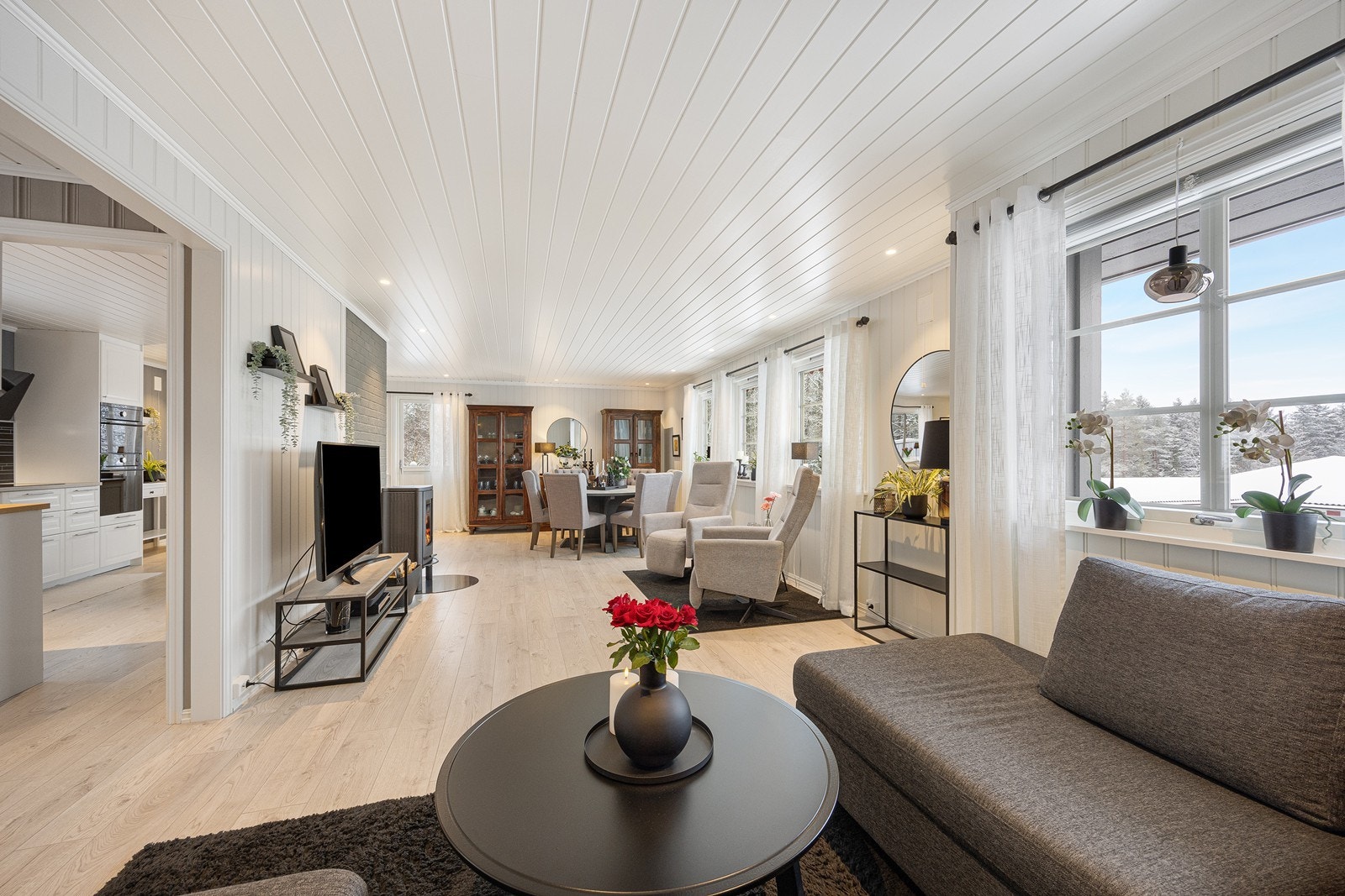 Dagslyset som strømmer inn via store vinduer gjenspeiles fint i de lysmalte overflatene, og det er lagt lyst, enstavs laminat på gulvet. Galleribilde