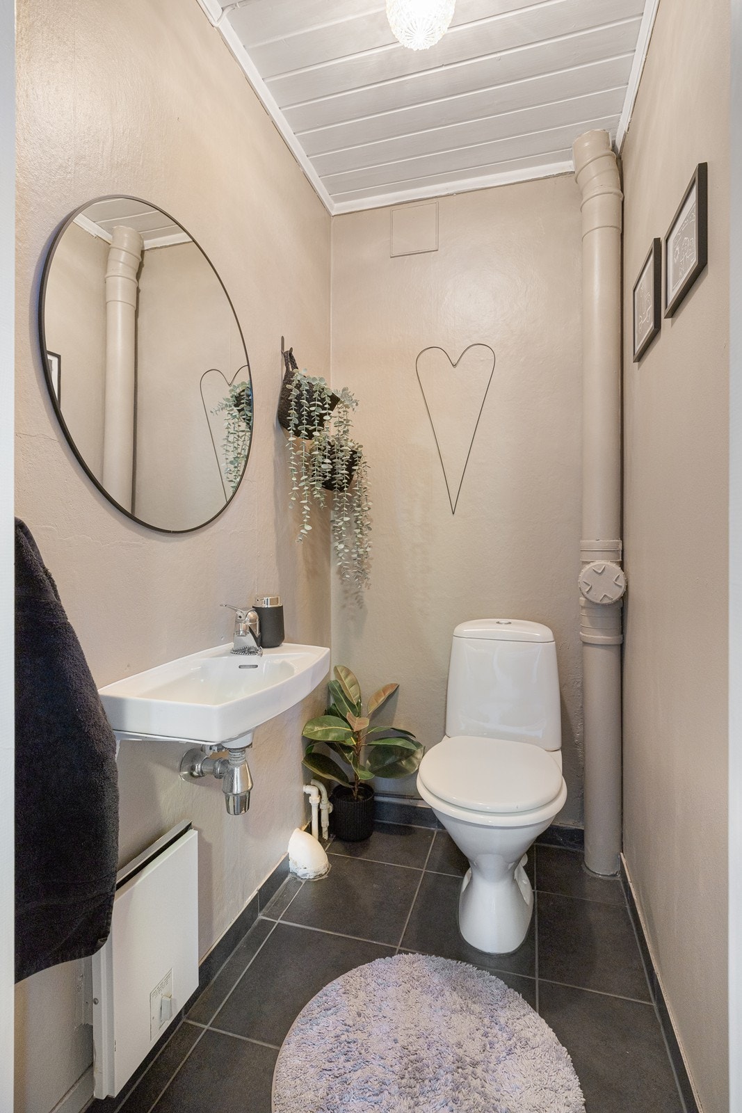 WC-rommet i underetasjen har lysmalte vegger og grå fliser på gulvet, og rommet har toalett, servant og god belysning. Galleribilde