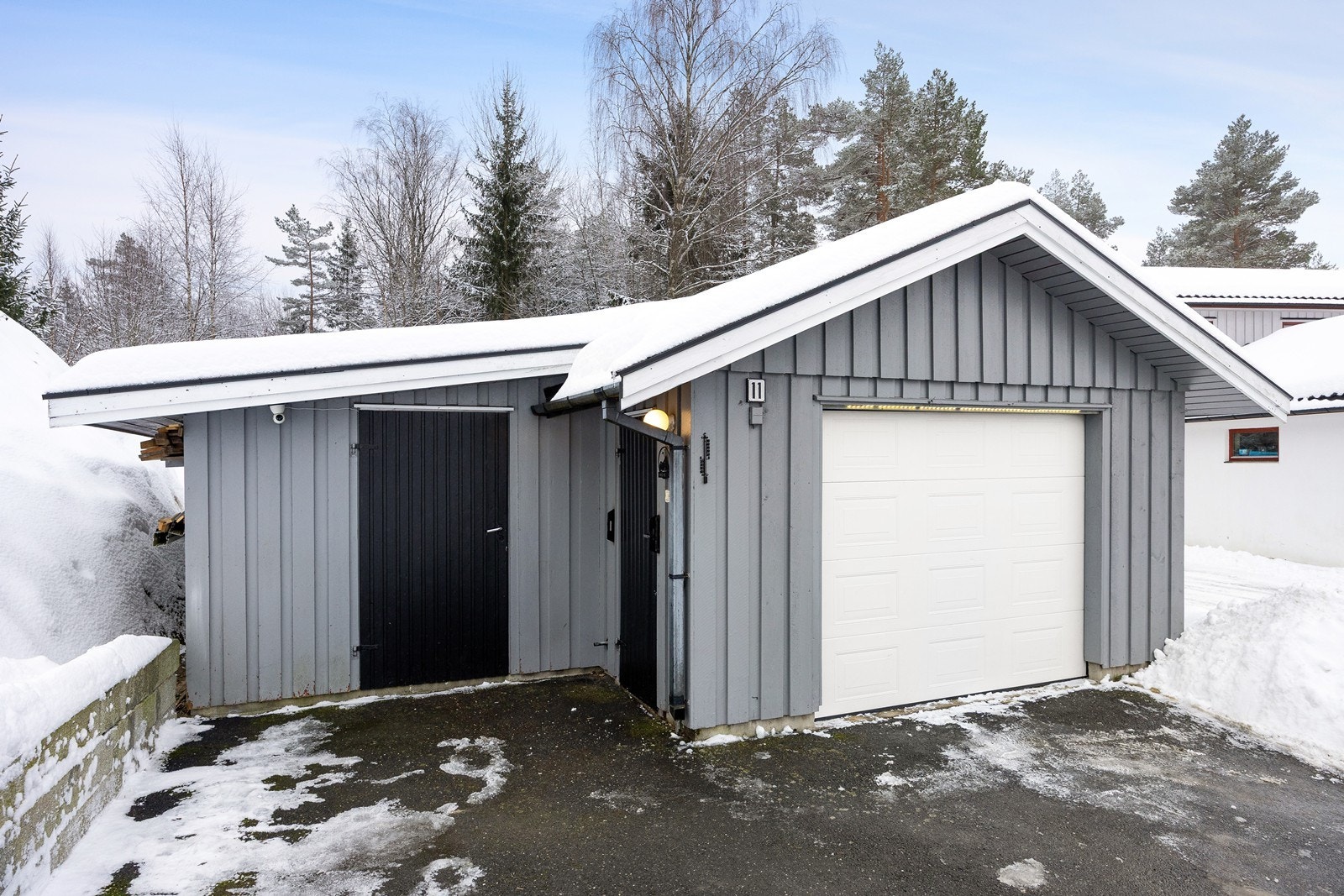 Garasjen er en frittstående enkel garasje med stor bod. Det er innlagt strøm i garasjen, og den er utstyrt med en leddport i metall. Galleribilde