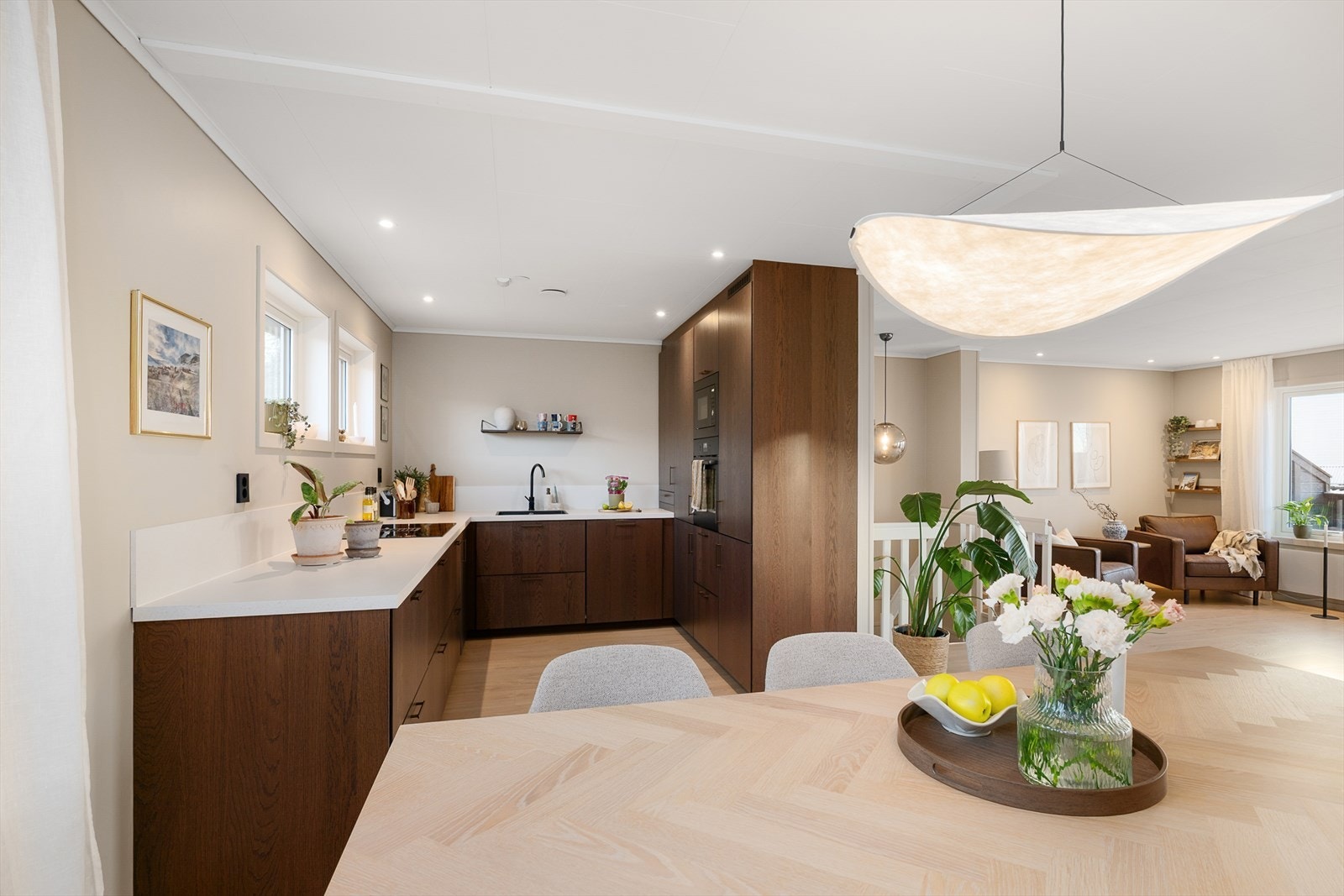 Kjøkkenet har en moderne innredning fra 2024 med brune, glatte fronter og hvit laminert benkeplate med underlimt oppvaskkum. Galleribilde