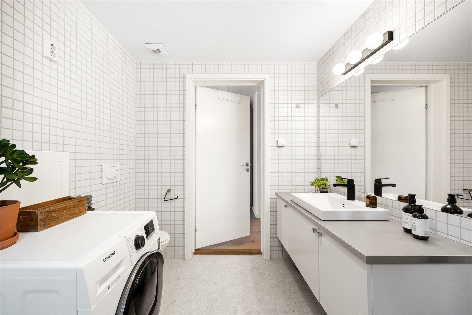 Rommet er utstyrt med vegghengt toalett, dusjhjørne med svingbare glassdører og baderomsinnredning med skuffer, nedfelt servant og speil. Galleribilde