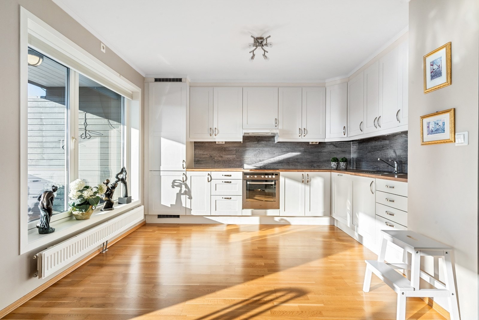 Praktisk og funksjonell kjøkkeninnredning med hvitlakkerte fronter og laminert benkeplate. Galleribilde