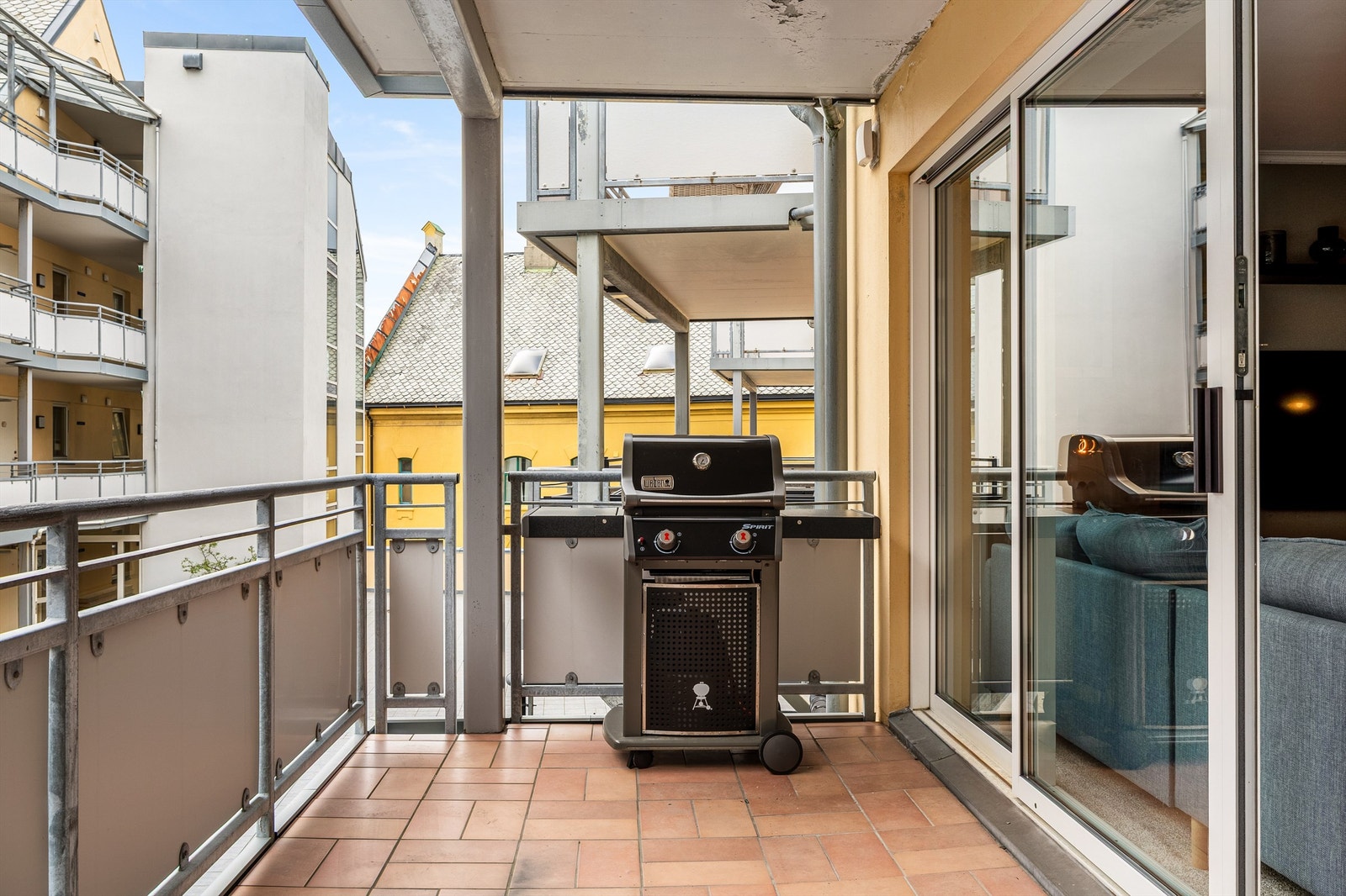 Romslig balkong på ca. 10 m² med flislagt dekke og rekkverk i metall Galleribilde