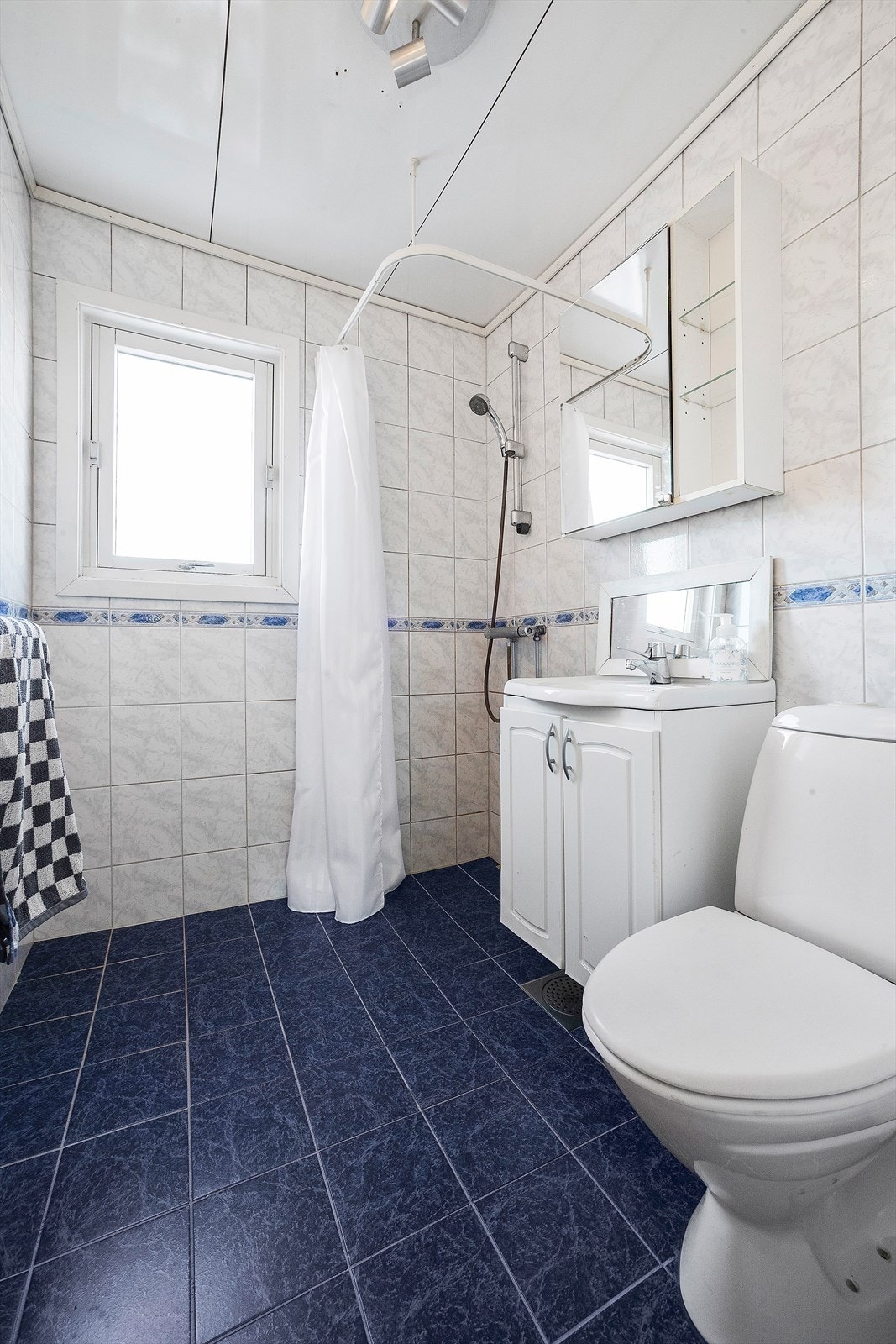 Flislagt bad med dusjhjørne, toalett og servant med underskap. Galleribilde